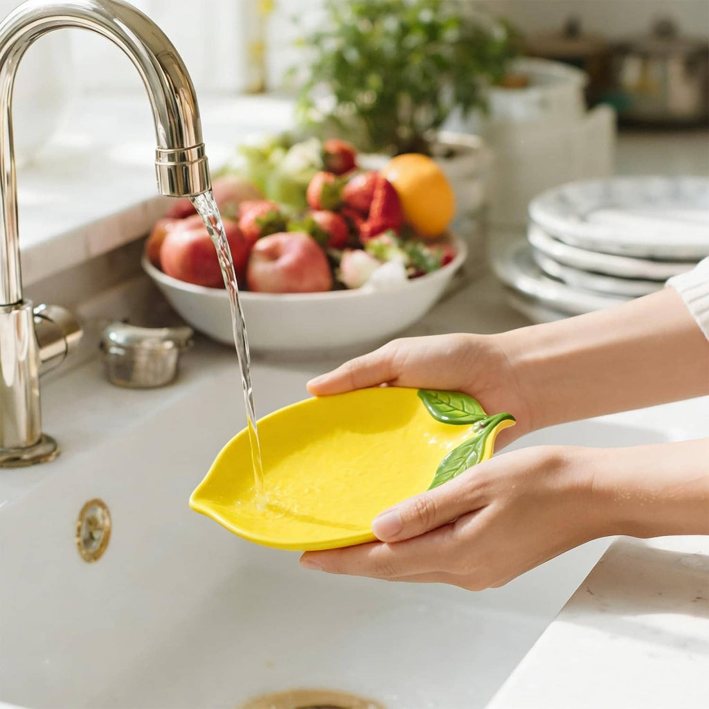 Yellow ceramic lemon-shaped spoon rest held in hand with green leaf detail