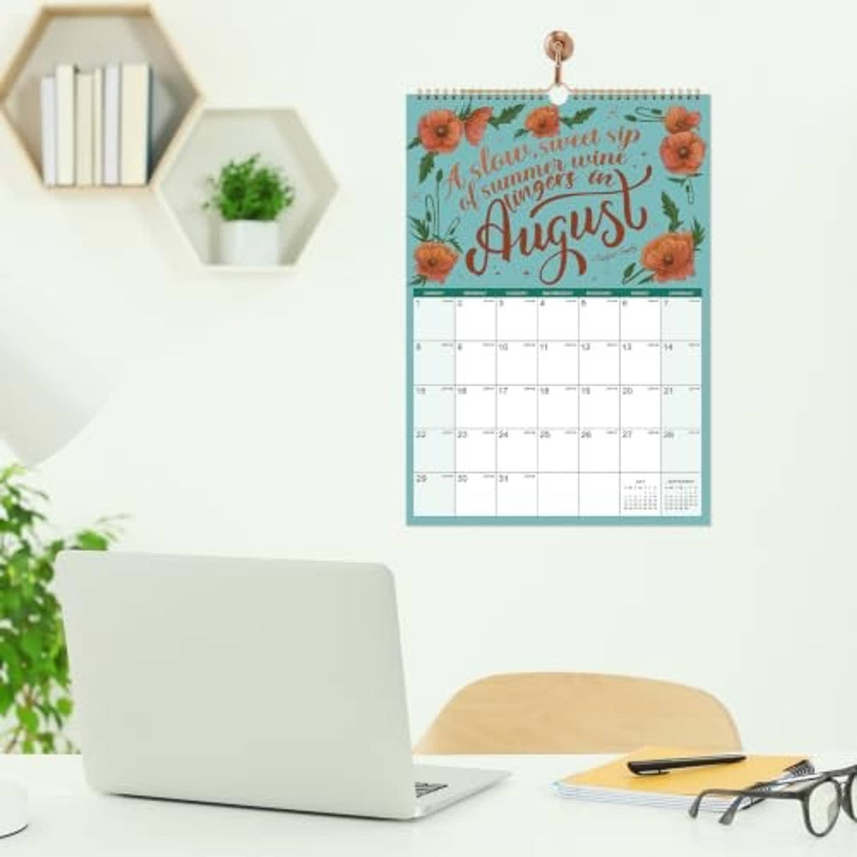 August 2027 wall calendar hanging with blue frame and colorful seasonal cover