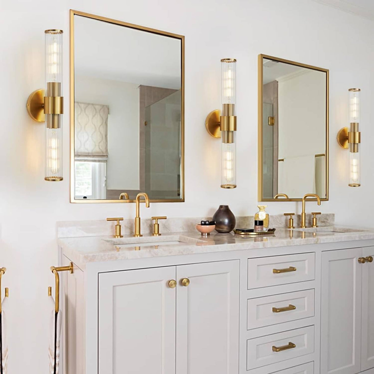 Gold vanity light 2-pack with clear glass tube shades flanking mirrors above a white vanity.