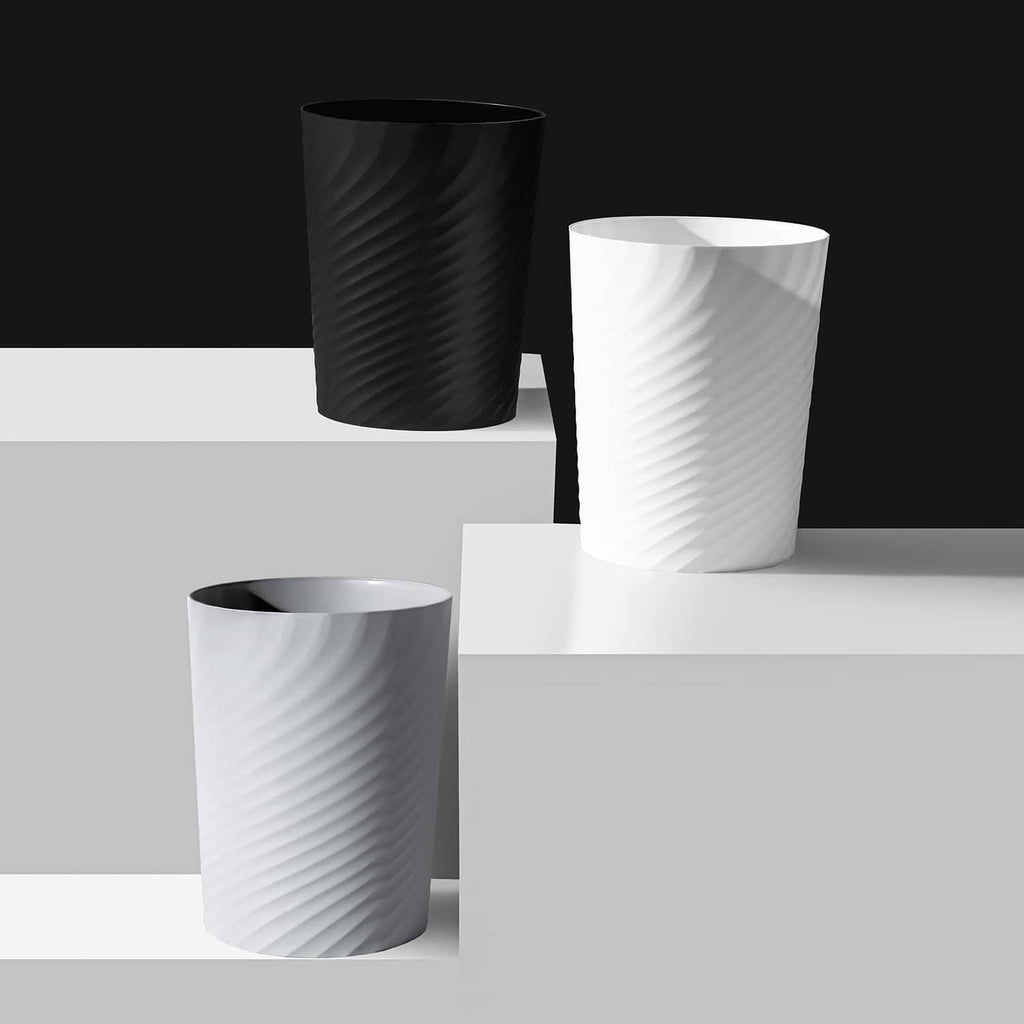 Set of white and dark plastic trash cans with ridged texture and open tops