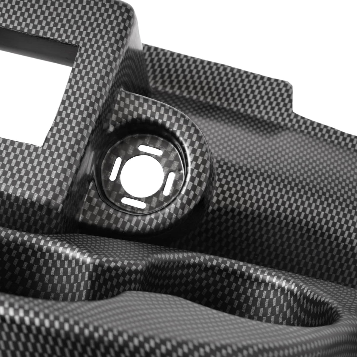 Close-up of carbon-fiber style dash cover with a round access hole and textured surface.