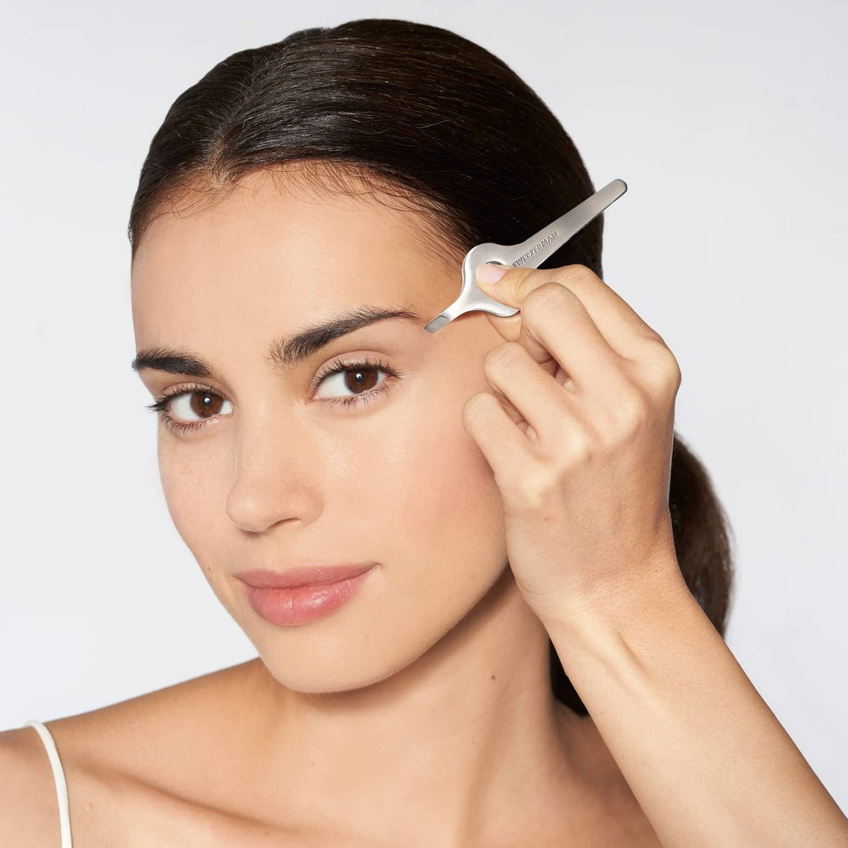 Wide grip slant tweezer held near eyebrow for precise grooming