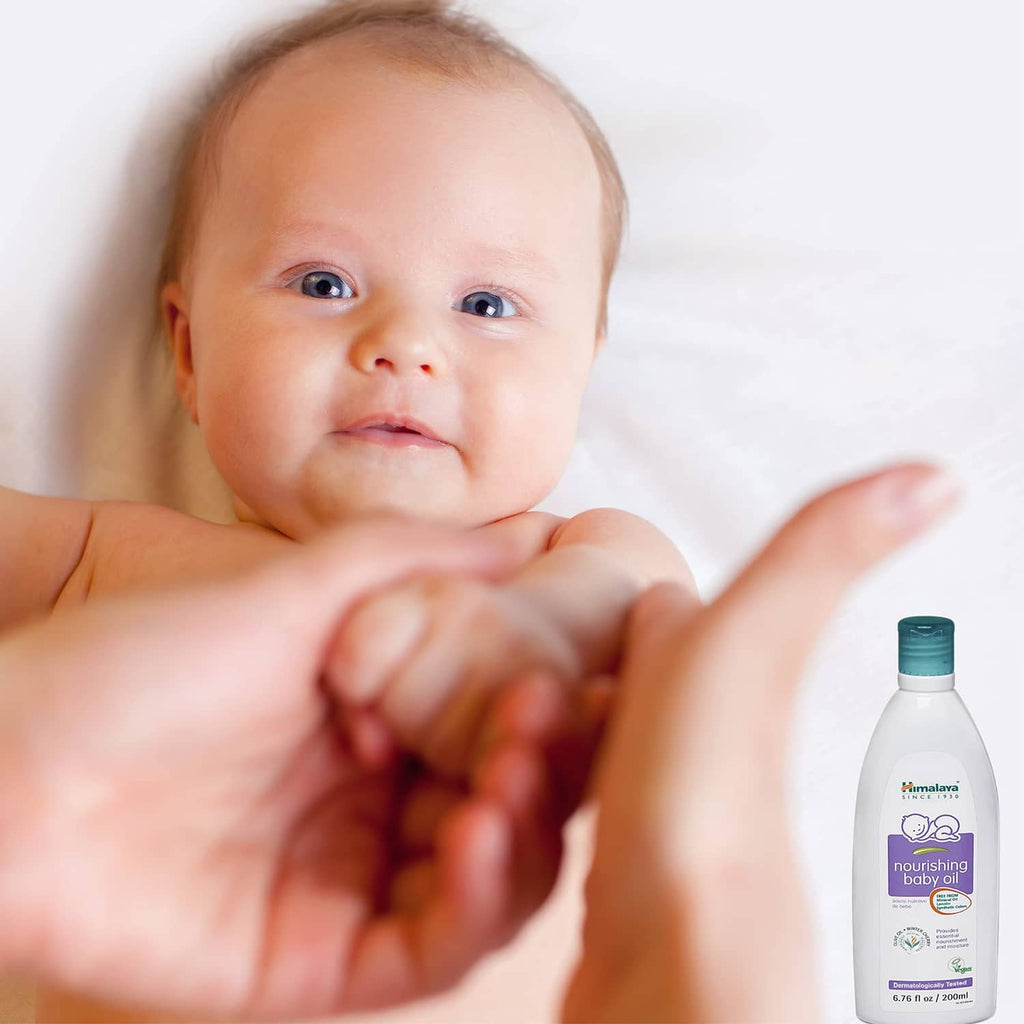 Baby smiling with baby oil bottle, white bottle with teal cap