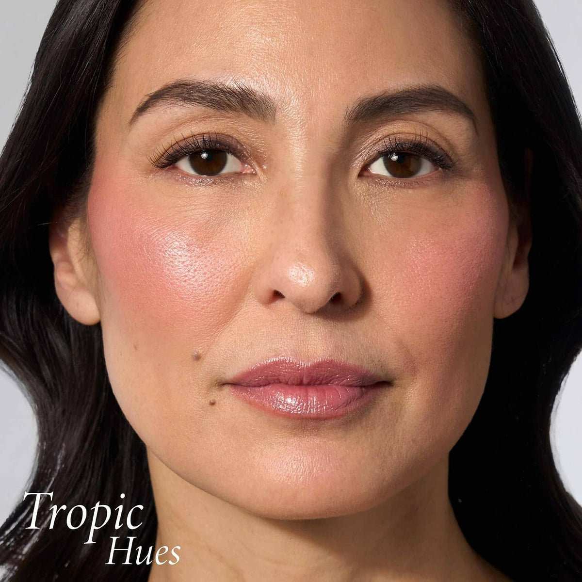 Face close-up with glowing blush in Tropic Hues pink-coral shade