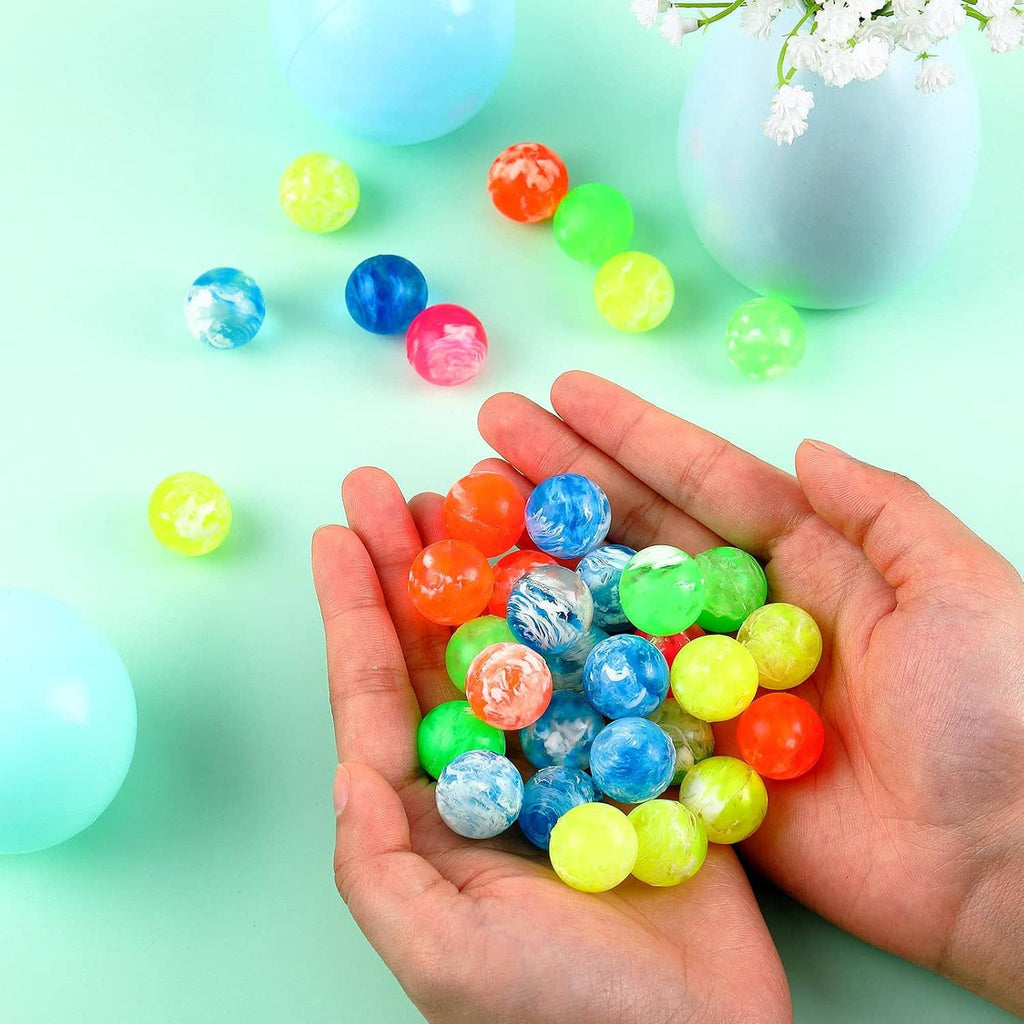 Small bouncy balls in an open palm, mixed bright neon and marbled colors.