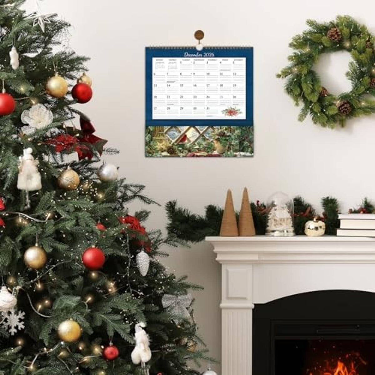 Wall calendar with pocket hanging in Christmas setting with tree, ornaments, and wreath
