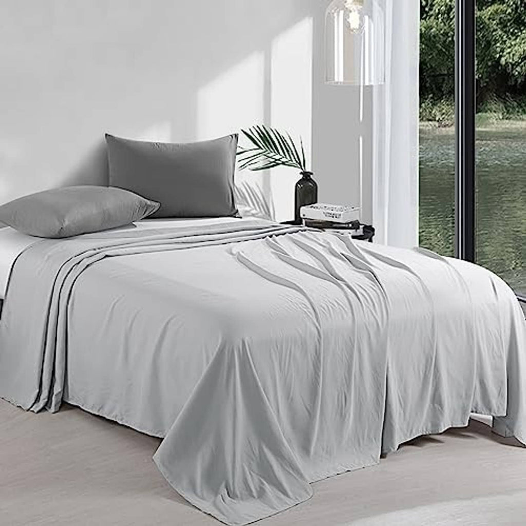 Light grey king flat sheet spread across bed with matching pillows