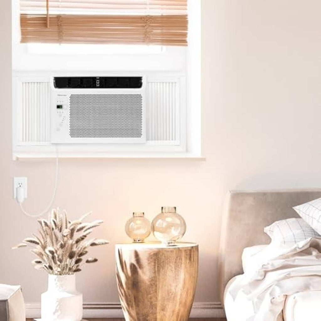 White window air conditioner in a wall window with front grille and control buttons