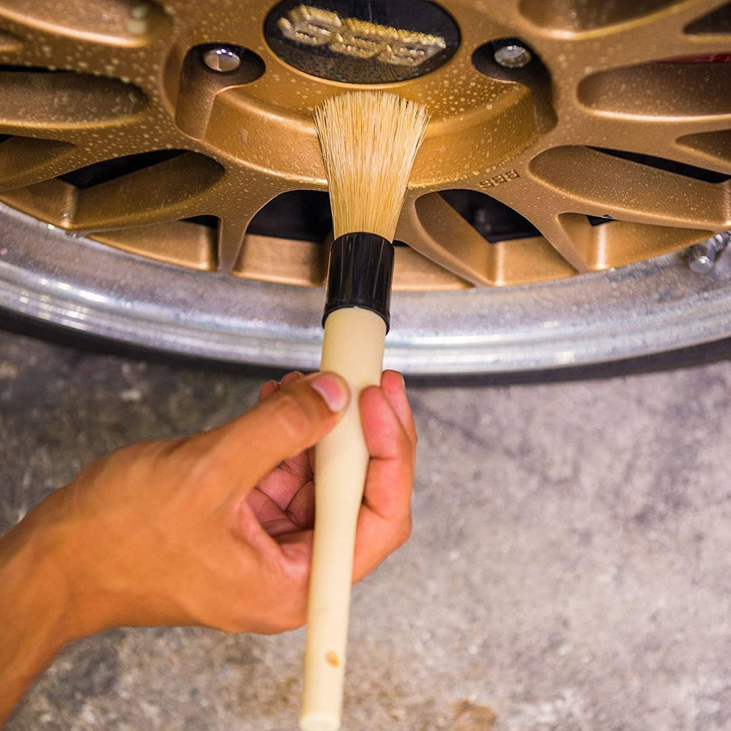 Boar hair brush scrubbing wheel spokes with tan bristles