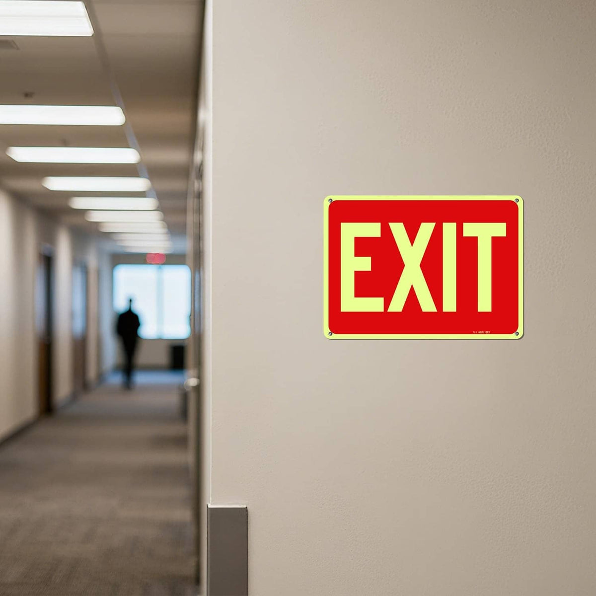 Red EXIT sign mounted in hallway, yellow letters with green glowing border