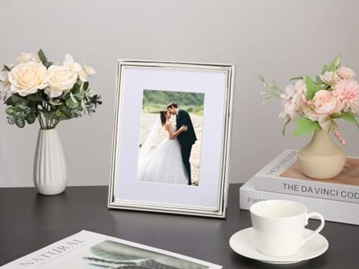 Silver metal picture frame on tabletop with white mat and wedding portrait photo