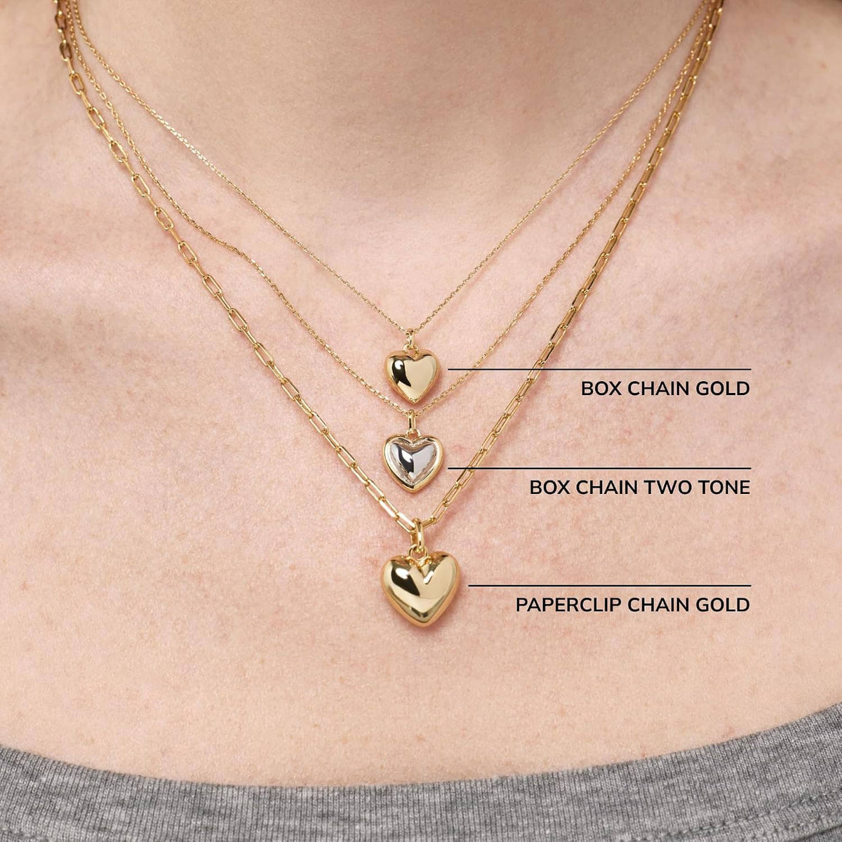 Layered gold-tone heart pendant necklaces with box and paperclip chains, close-up
