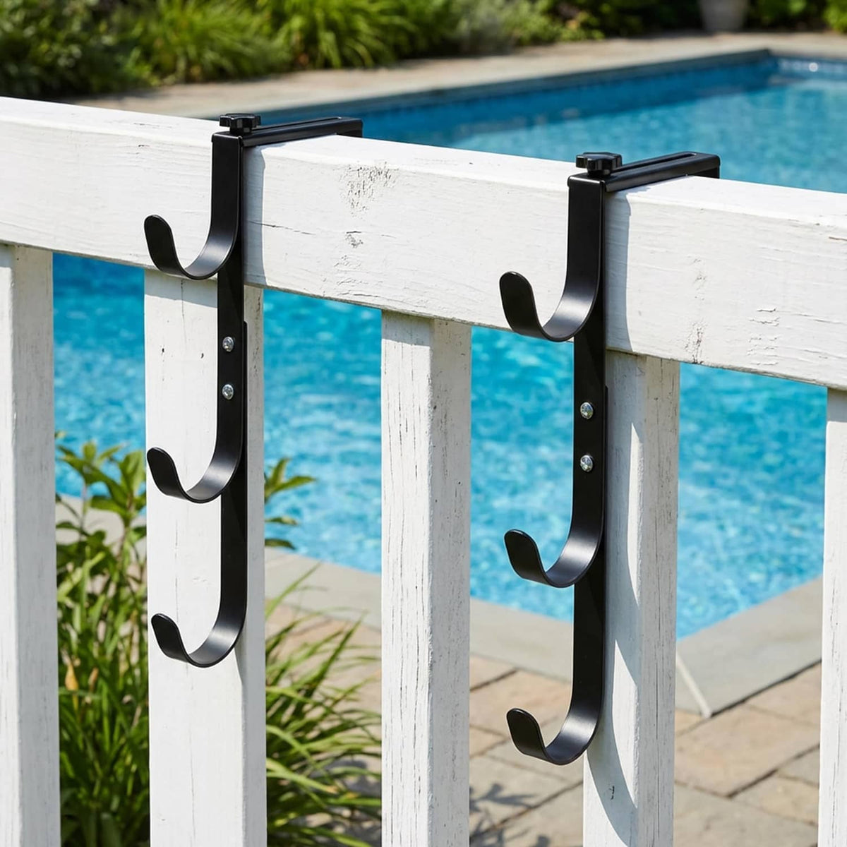 Set of black pool fence hooks mounted on a white fence rail
