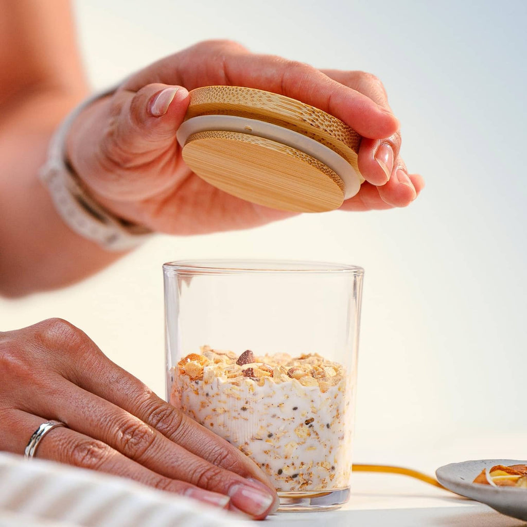 Glass of overnight protein oats topped with a wooden lid and sprinkled oats
