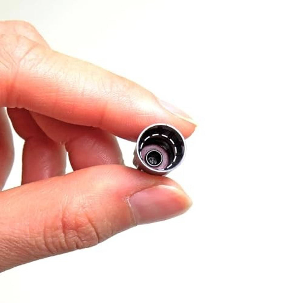 Black long tire valve stem cap held in fingers, open end showing insert