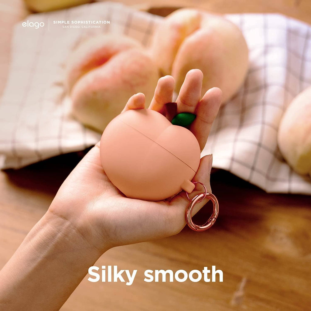 Peach silicone charging case cover with green leaf and rose-gold keyring in hand