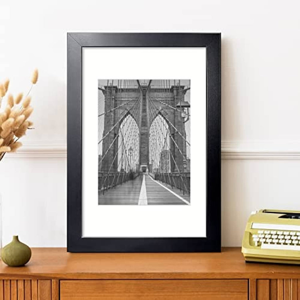 Black picture frame with mat, displaying a black-and-white bridge photo.