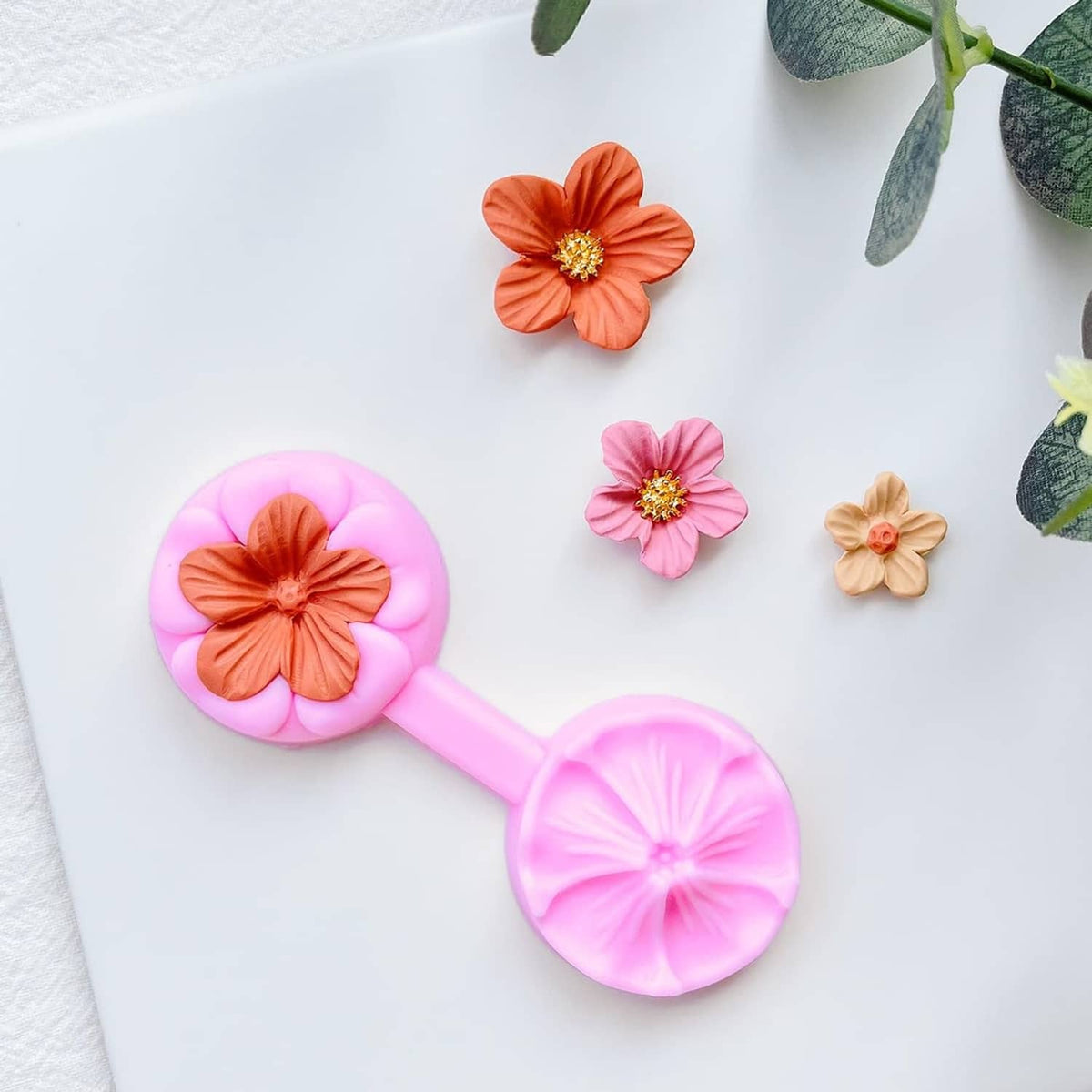 Pink flower petal cutter with orange, pink, and beige finished flower pieces