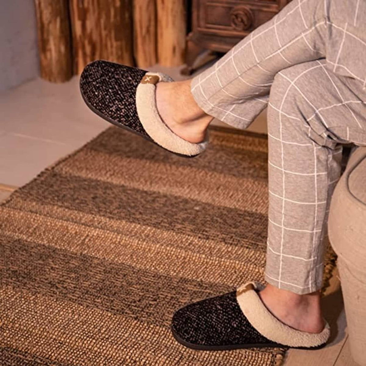 Sherpa-lined slip-on slippers worn indoors; dark speckled exterior and light fleece trim