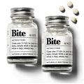 Bite whitening toothpaste tablets in a clear glass jar with metal lid and white tablets