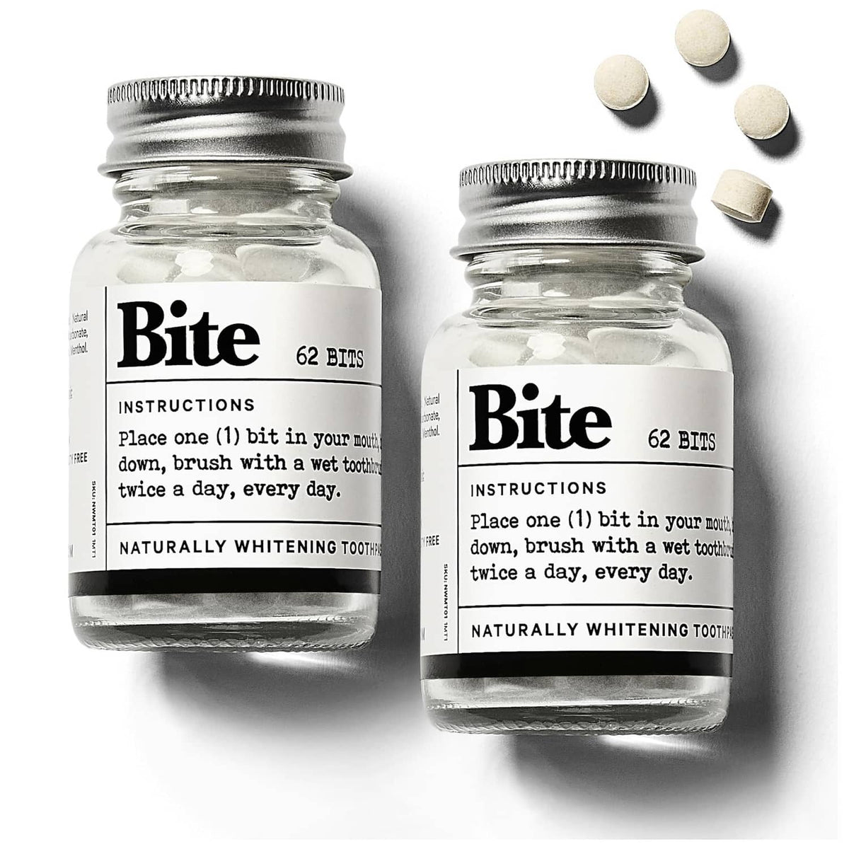 Bite whitening toothpaste tablets in a clear glass jar with metal lid and white tablets