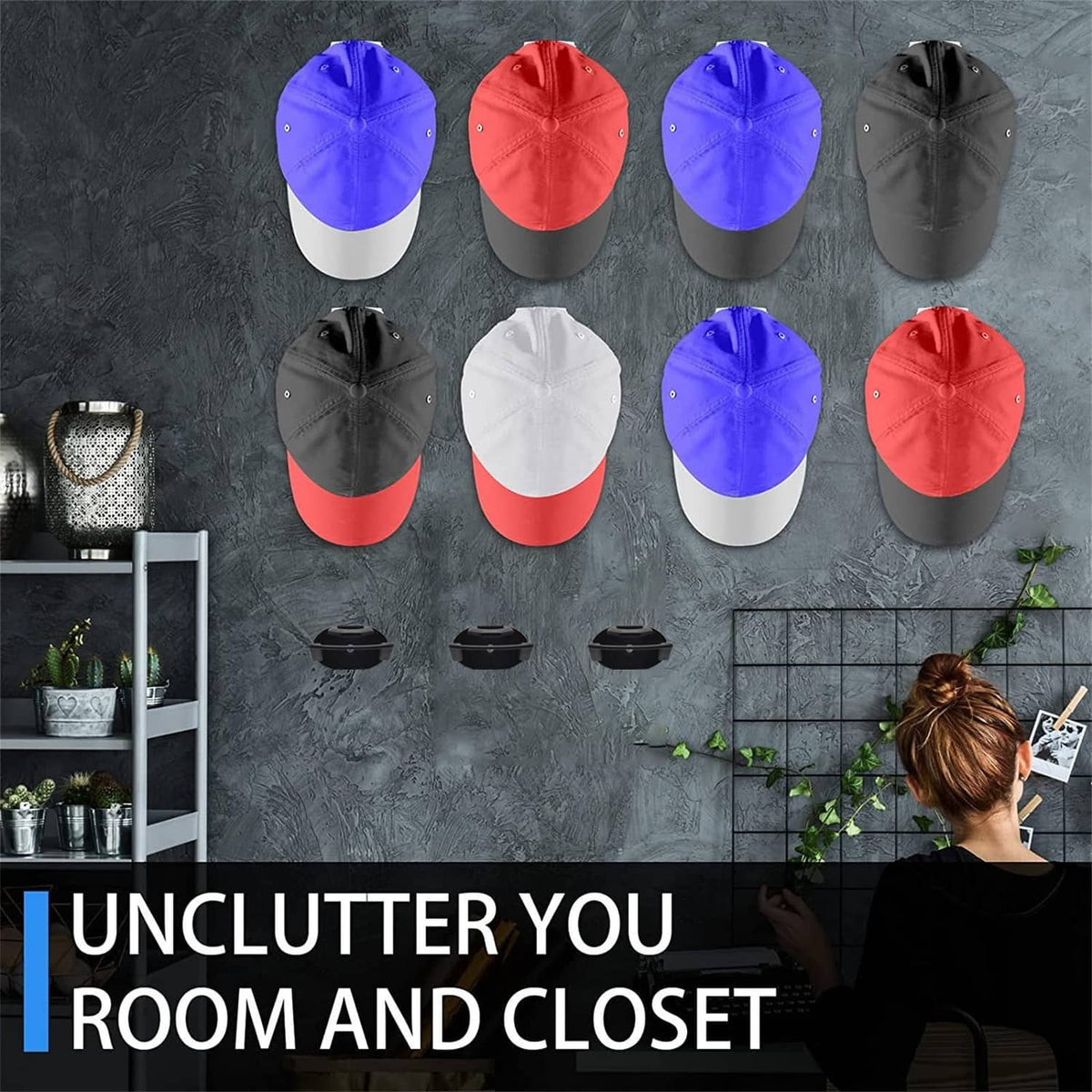 Multiple baseball caps hanging on black adhesive hat hooks on a wall