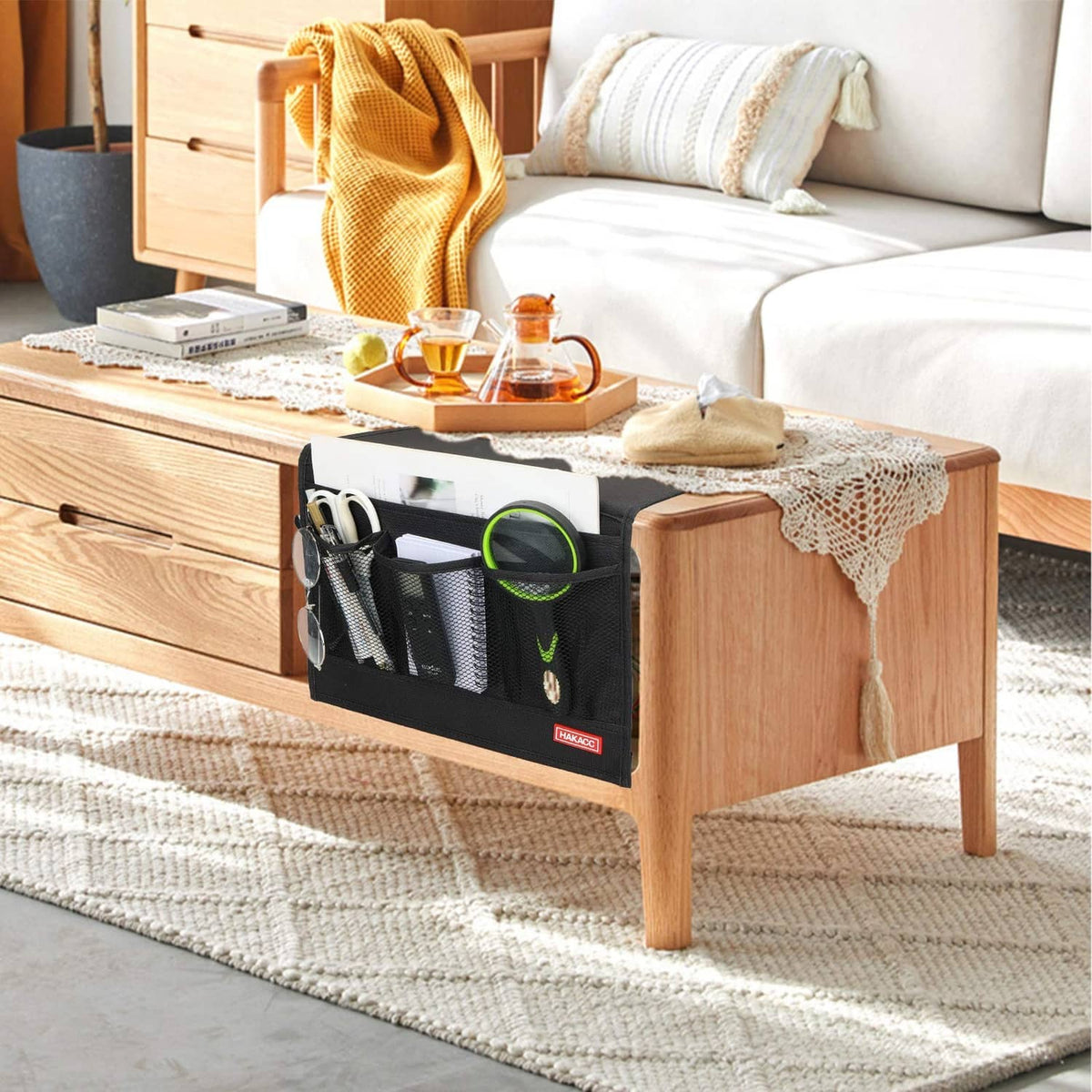 Black bedside storage caddy with front pockets for personal items on a bed