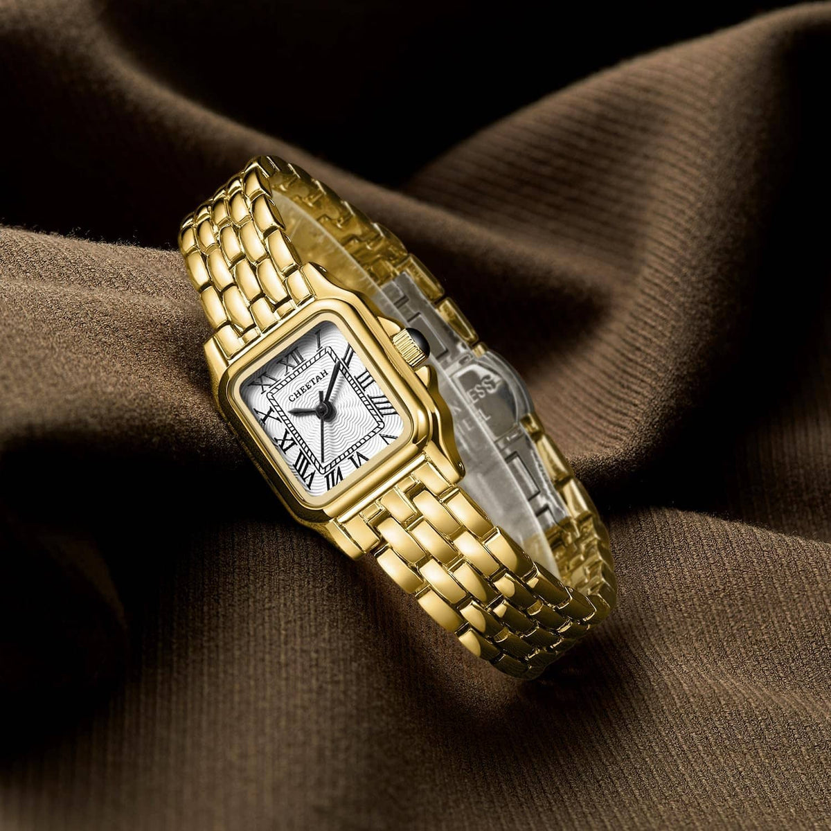 Gold-tone square wristwatch on wrist with white Roman numeral dial and textured band