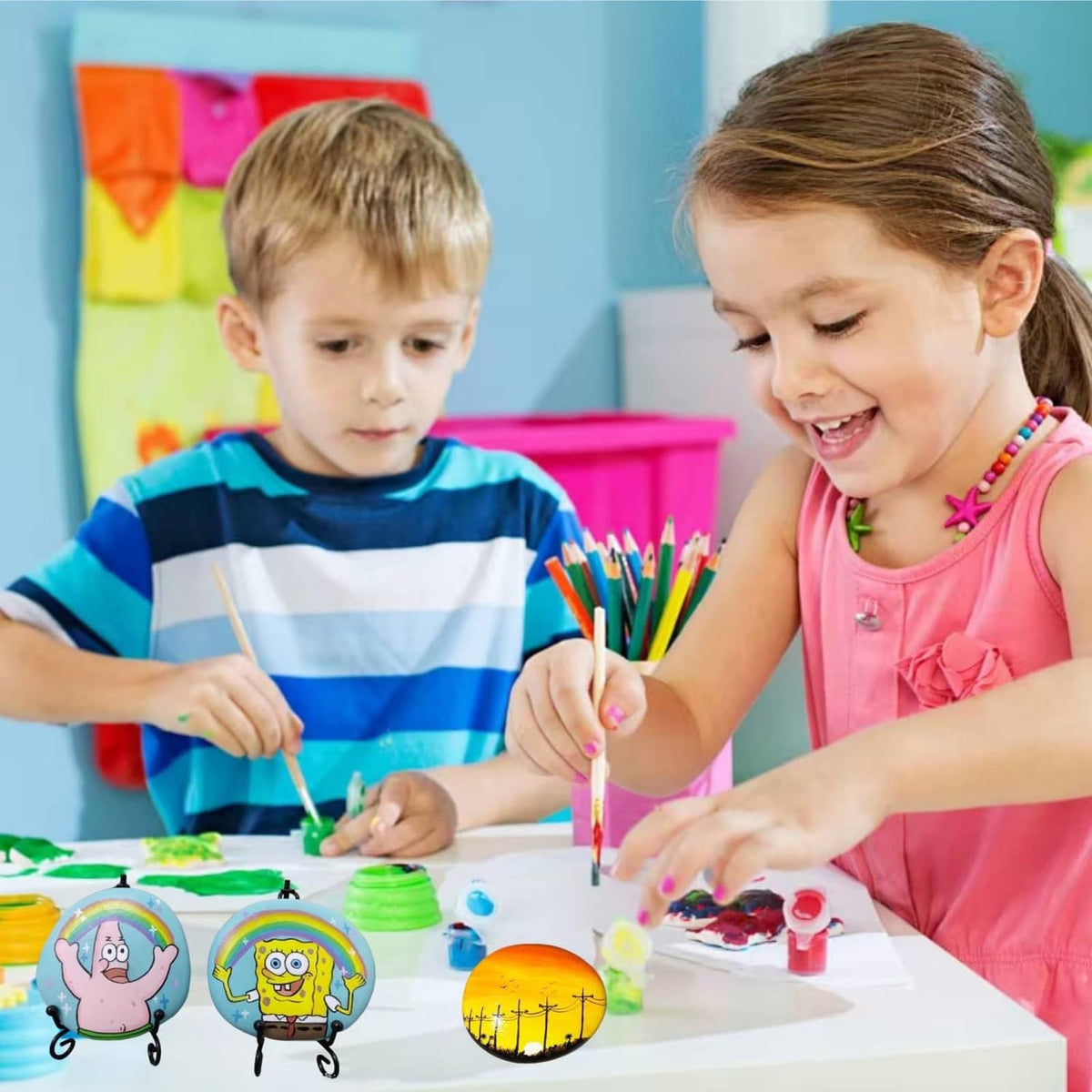 Children painting small oval craft rocks with markers and paints at a table