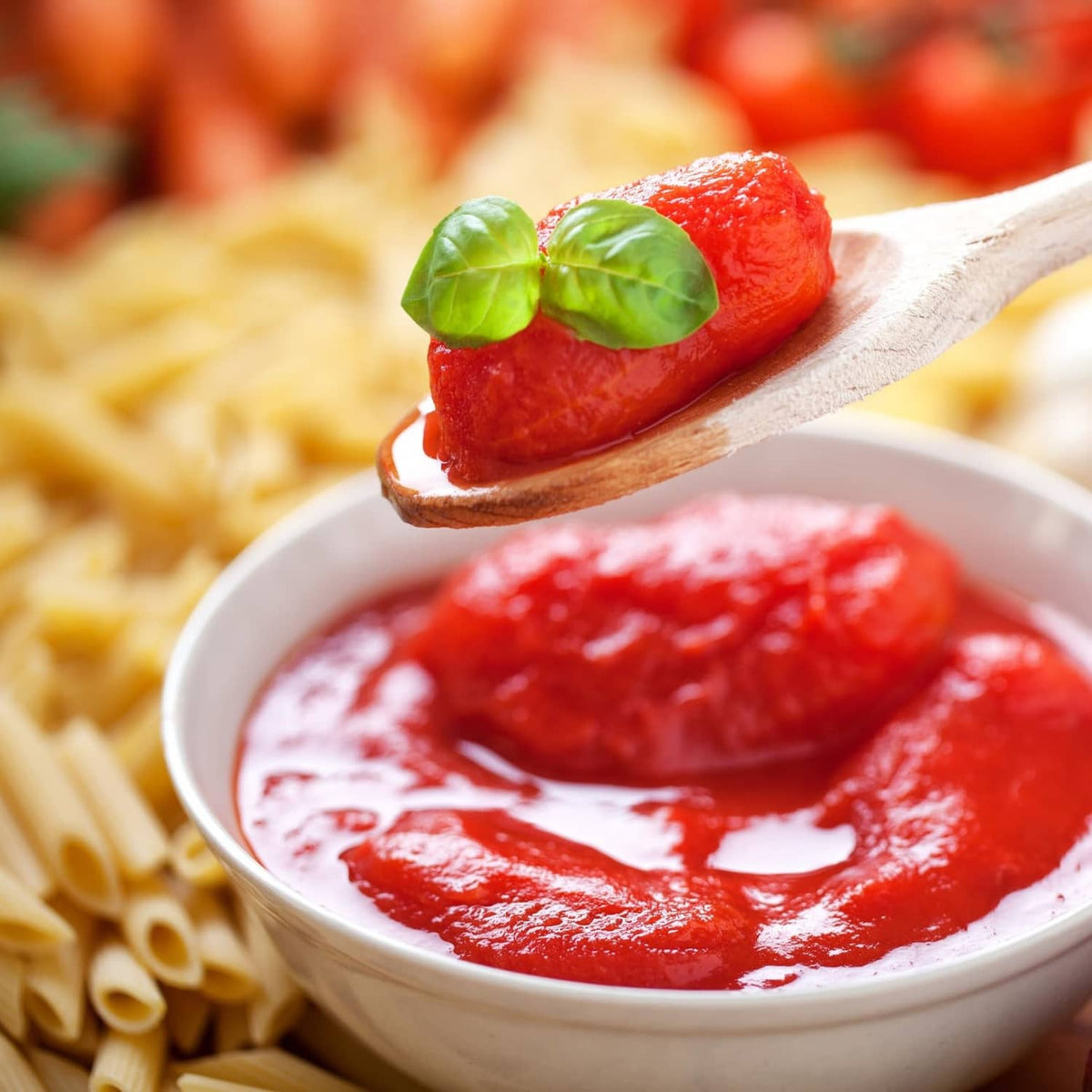 Ground peeled tomato sauce in bowl with basil leaves