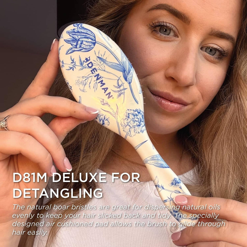Blue floral Denman paddle hair brush held near hair, bristle side facing up