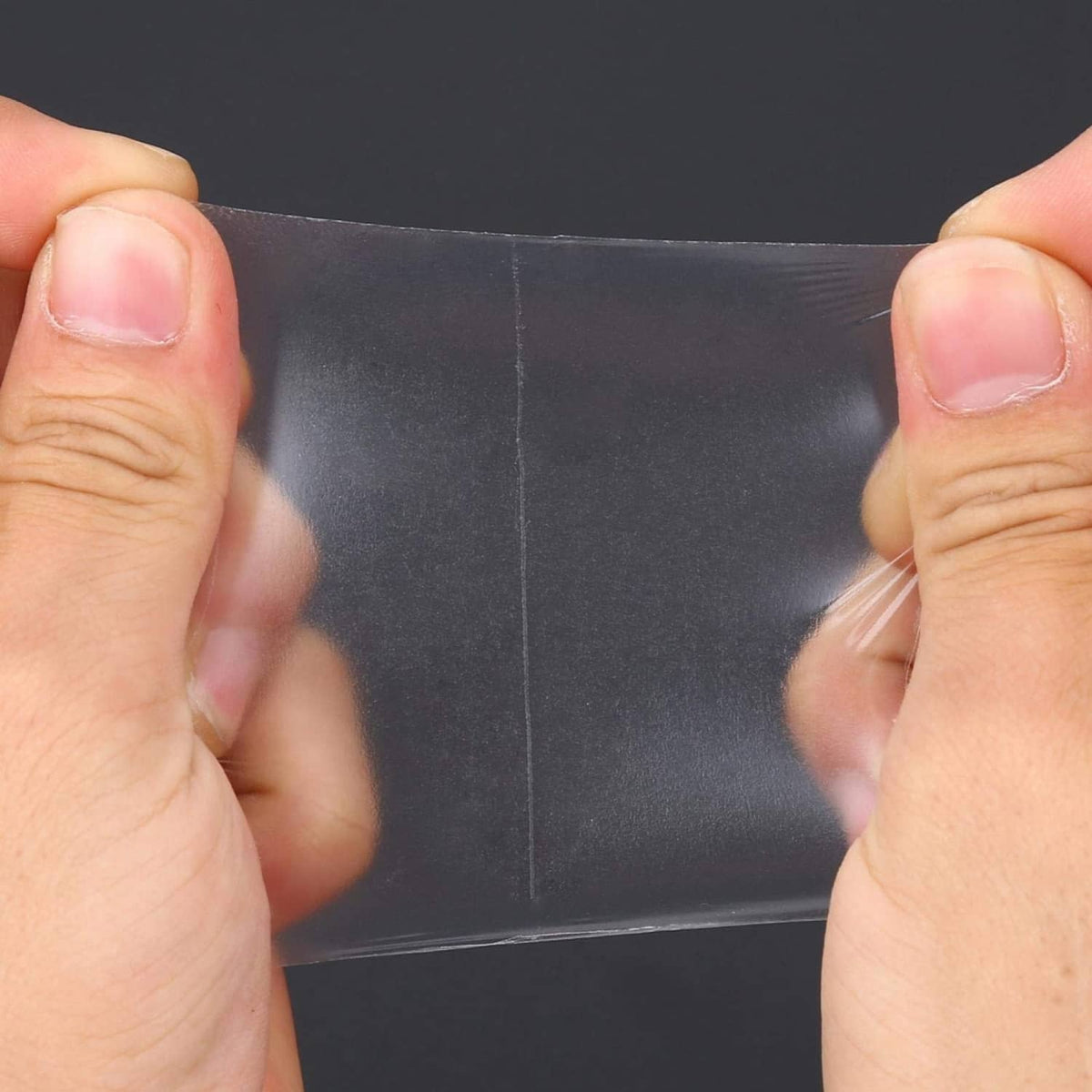 Clear underarm sweat pad adhesive sheet held between fingers for armpit coverage