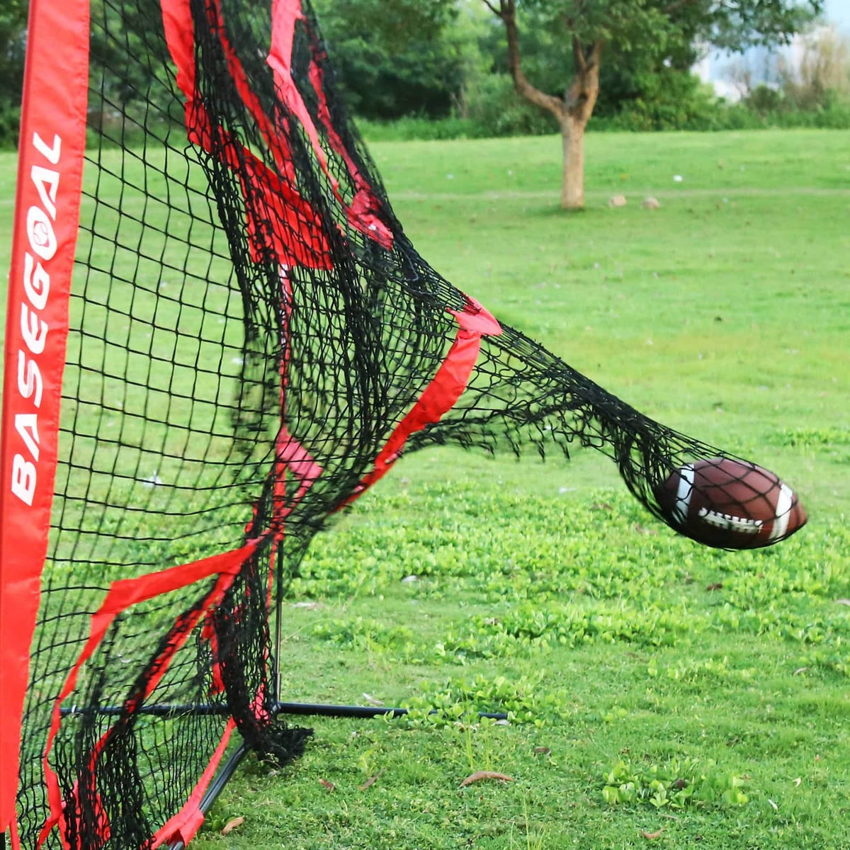 Red and black training net with target holes, football on outdoor grass