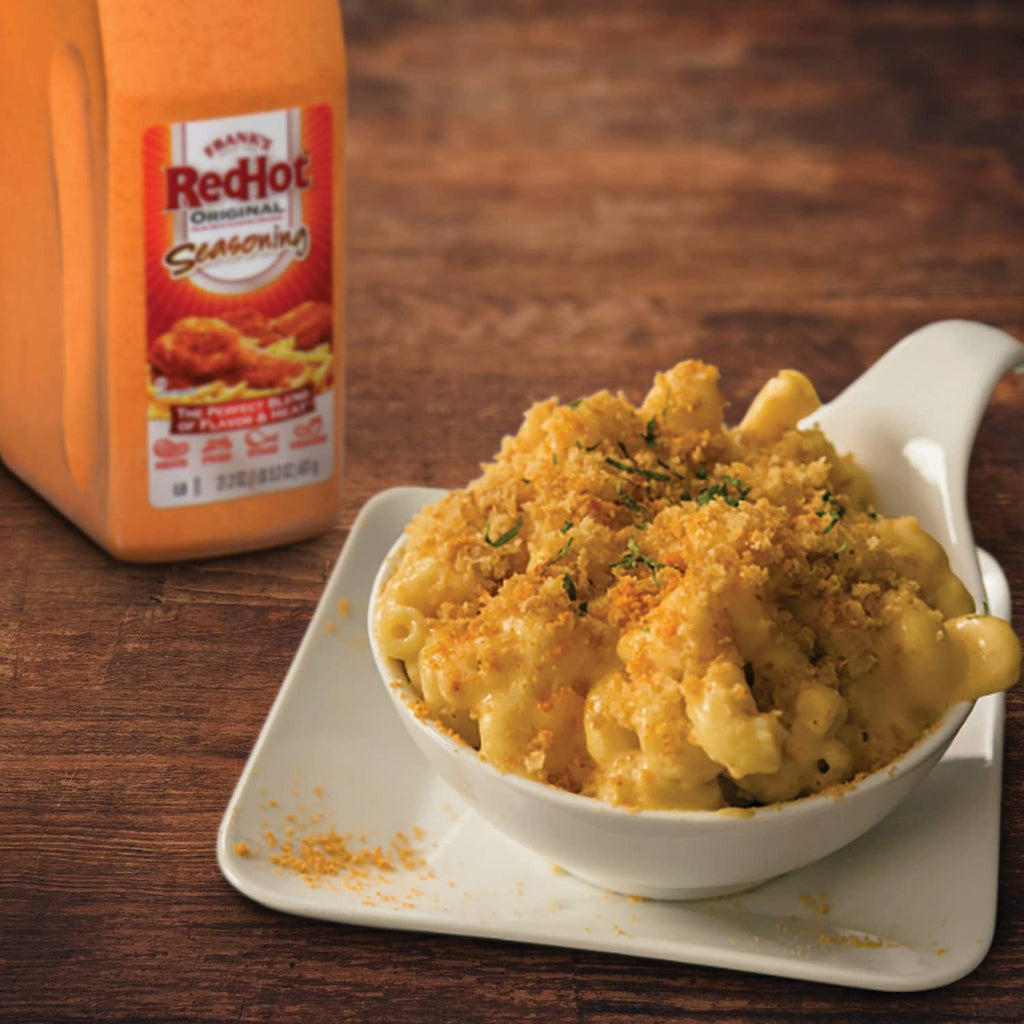 Bowl of seasoned pasta with orange-brown seasoning container in background