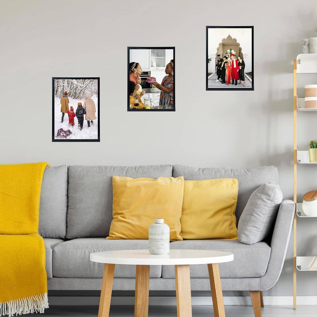 Black picture frames on a living room wall, each holding a small printed photo