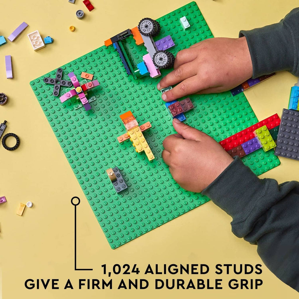 Green square LEGO baseplate with raised studs, colorful pieces arranged across it.