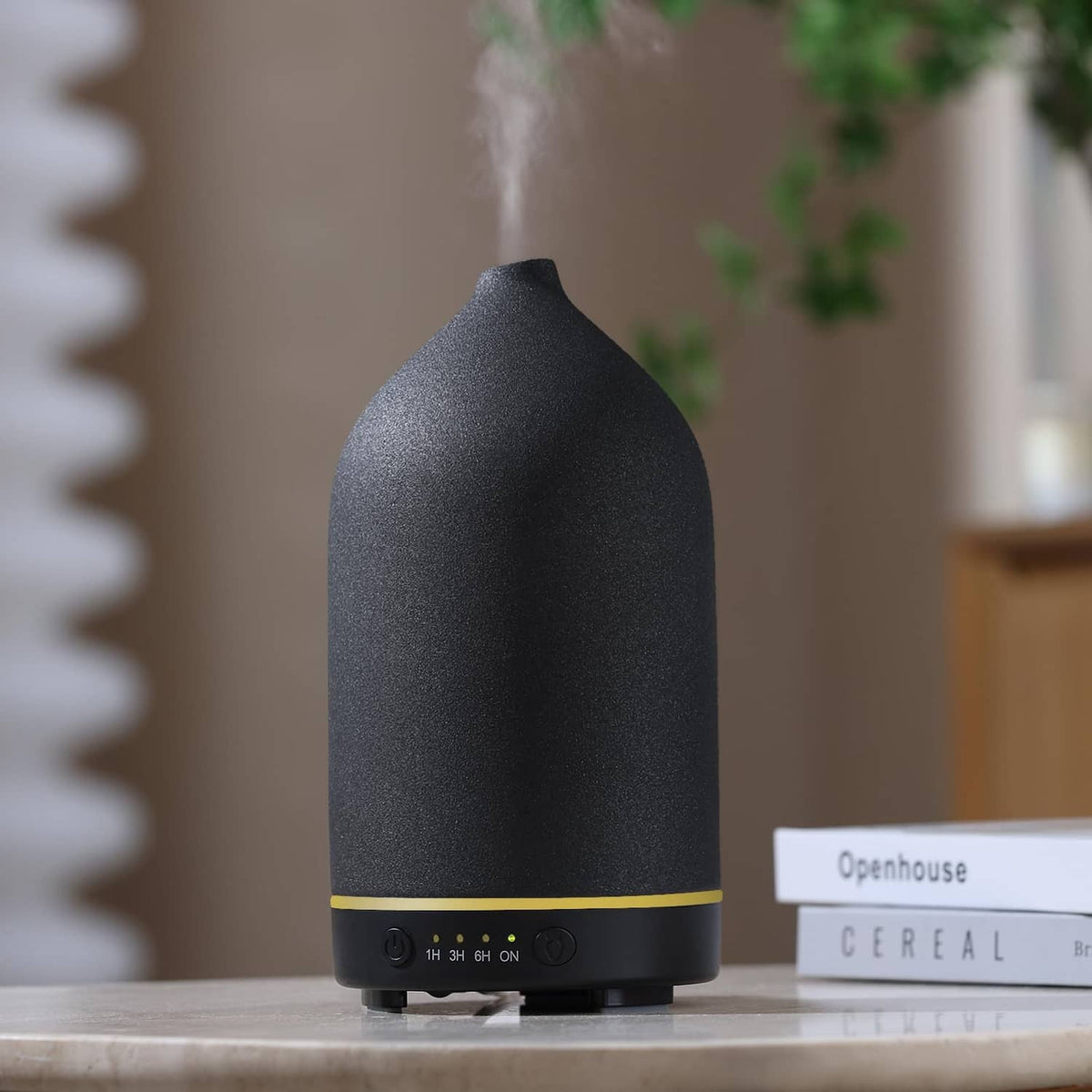 Black matte stone-finish essential oil diffuser with nozzle opening on a tabletop