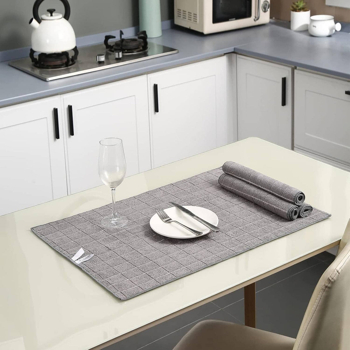 Grey microfiber towels folded on a kitchen countertop, set includes multiple rolls.