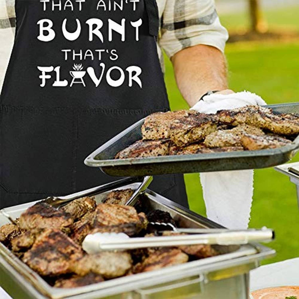Black chef apron with “That Ain’t Burnt That’s Flavor” slogan in outdoor grilling scene.