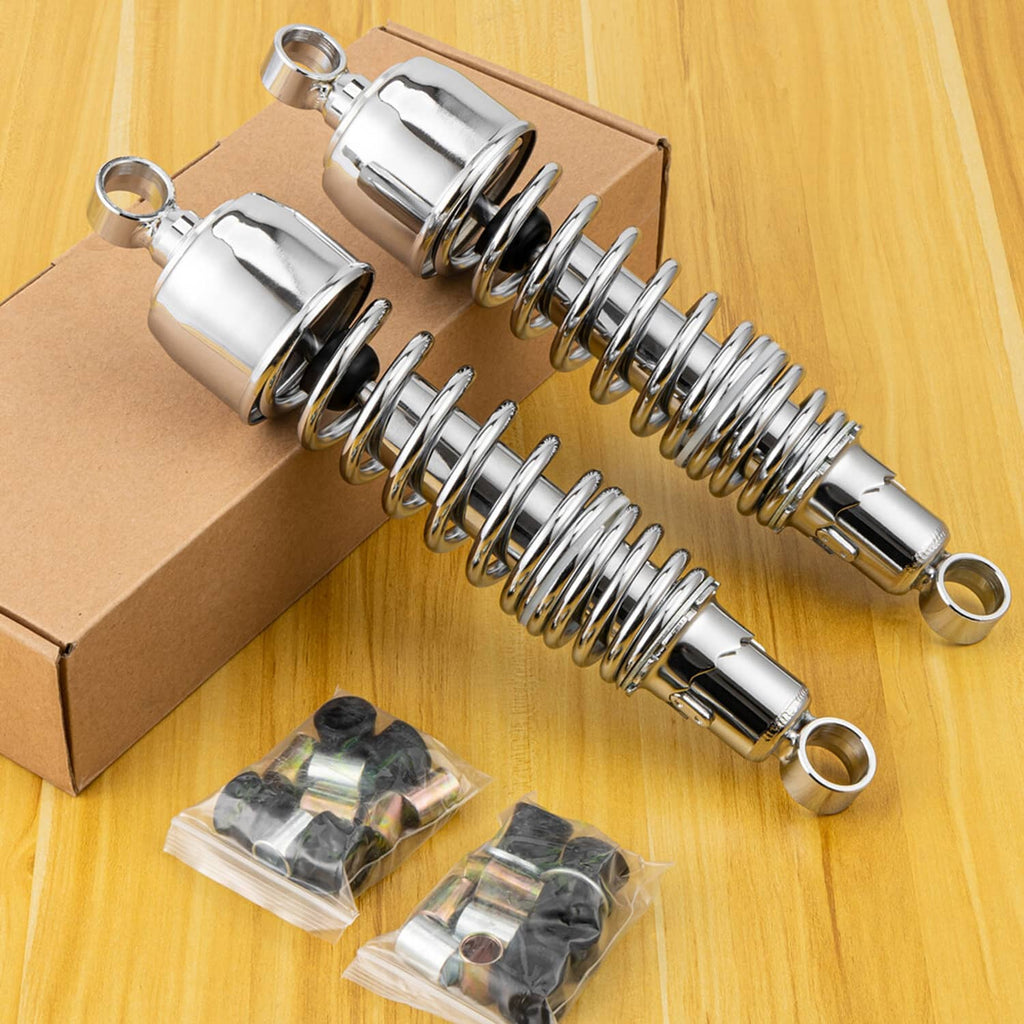 Two chrome rear shock absorbers with coiled springs beside included mounting hardware in box