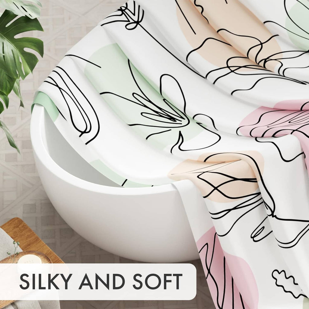 White shower curtain fabric with pastel floral line pattern, draped over a bathtub rim