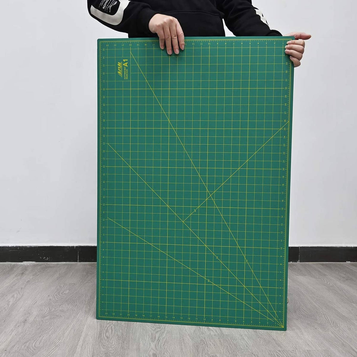 Large green self-healing cutting mat standing upright with measurement grid lines
