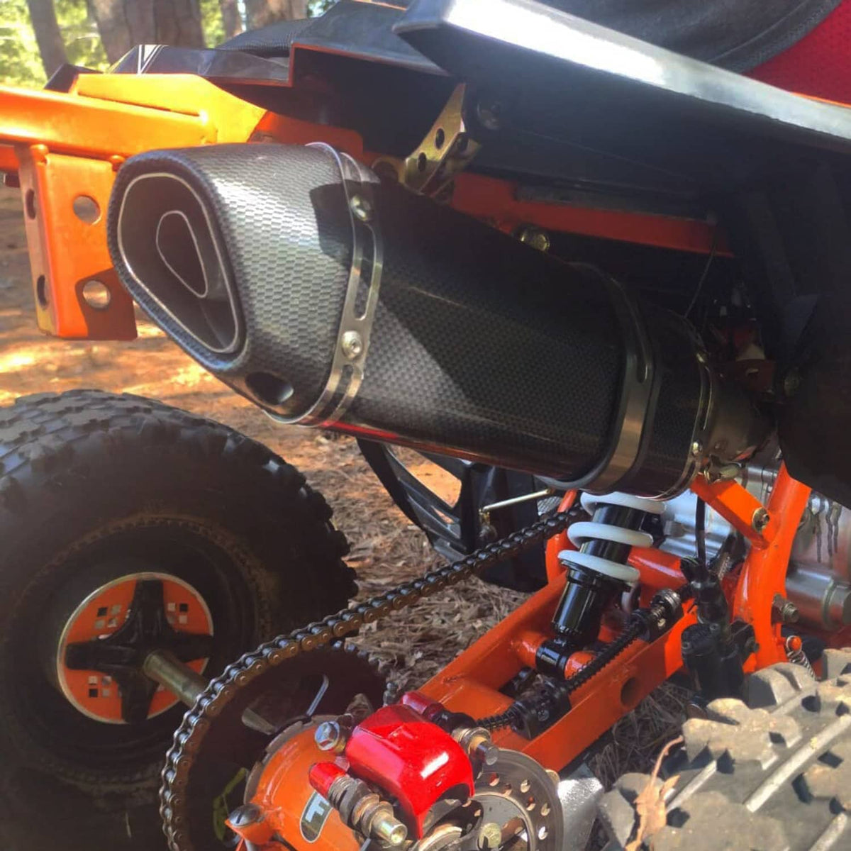 Installed motorcycle exhaust muffler with carbon-fiber sleeve and stainless outlet
