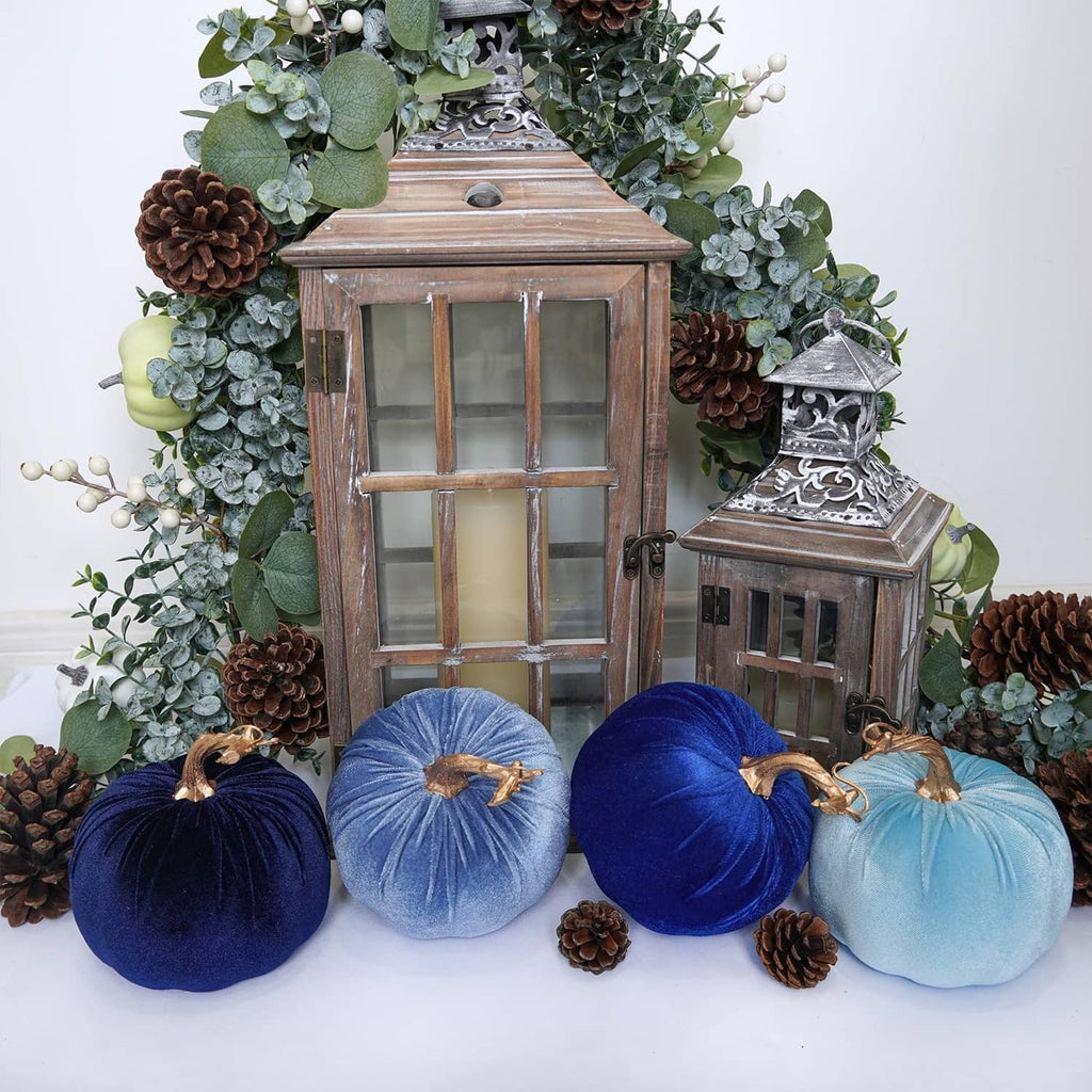 Assorted navy and light-blue faux velvet pumpkins with gold stems and hanging loops on display