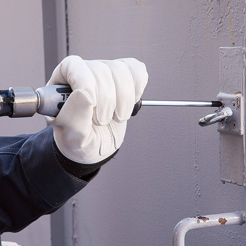 Gloved hand holding impact cross-point screwdriver driving a screw into a panel.