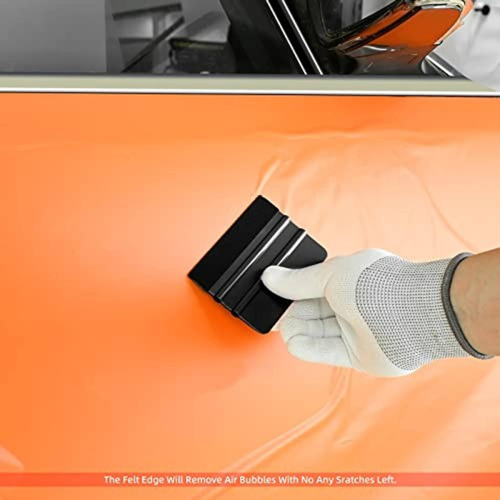 Black felt-edge vinyl squeegee removing bubbles on orange film with glove