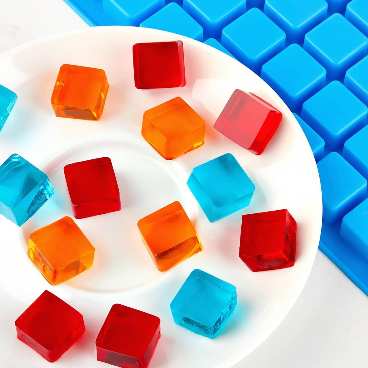 Square candy pieces on a plate with blue silicone mold tray nearby