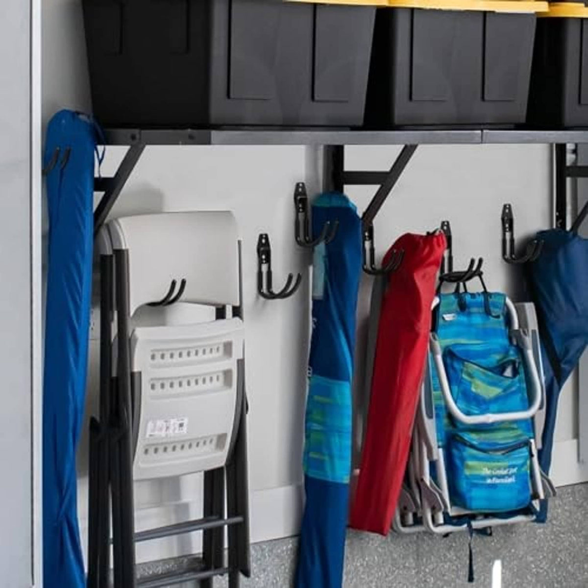 Black wall-mounted hooks organizing coats, bags, and tools in a storage area