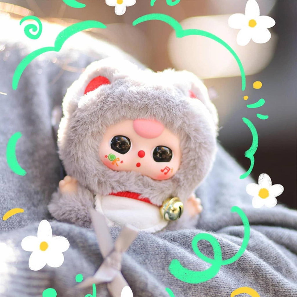 Close-up of a gray plush cat doll with pink blush and a bell collar.