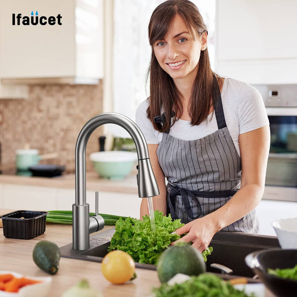 Stainless steel kitchen faucet sprayer head in use over a sink